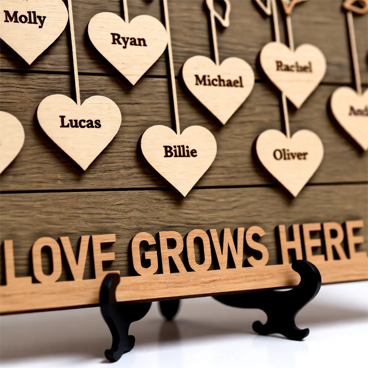 Wooden hearts with engraved names hanging from a family tree branch with 'Love Grows Here' along the bottom of the sign.