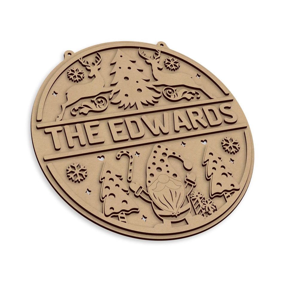 A round personalised plaque with a Christmas tree, reindeer, snowflakes, and the text 'THE EDWARDS', shown on a plain white background.